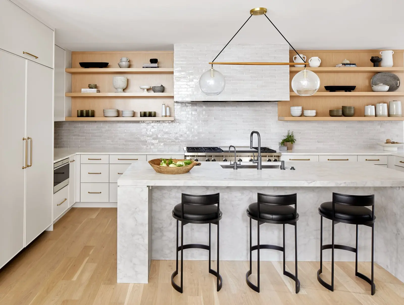 A Westfield kitchen with marble waterfall island, oak shelves and brass details