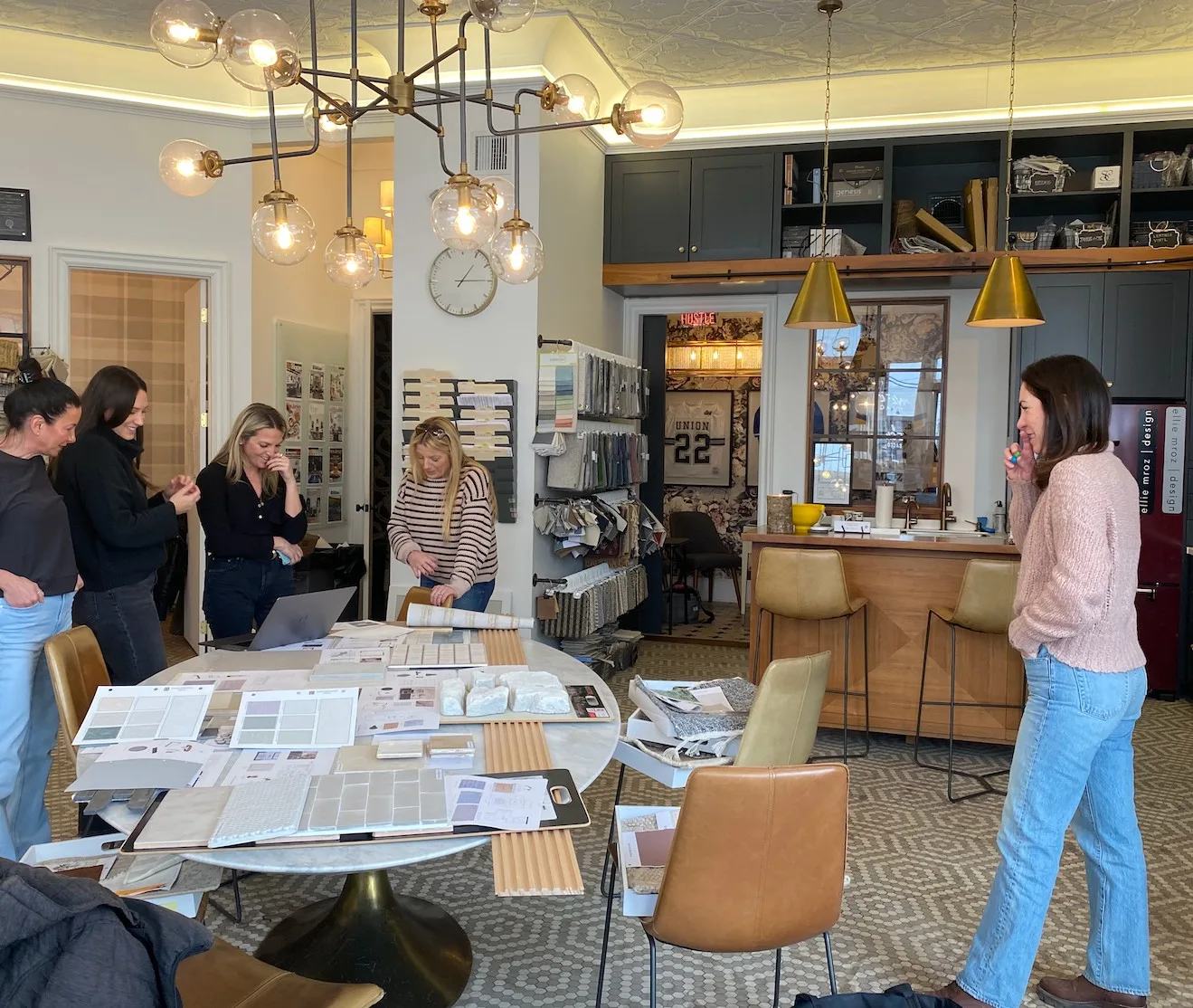 Ellie Mroz Design colleagues reviewing tile, stone, fabric and paint selections around the studio table